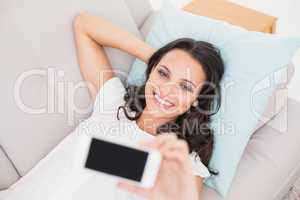 Pretty brunette taking a selfie on couch