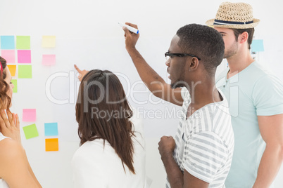 Rear view of coworkers writing on sticky notes