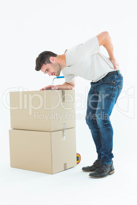 Delivery man with cardboard box suffering from back ache