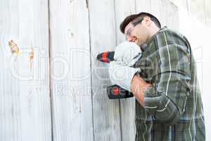 Worker using hand drill on wooden cabin