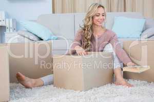 Pretty blonde on carpet with boxes holding book