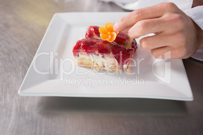 Close up of baker putting flower on the pastry with fruit