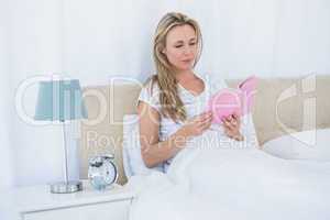 Concentrated blonde reading a book in bed