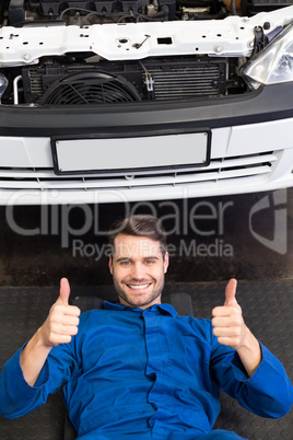 Mechanic lying and working under car