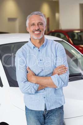 Smiling customer leaning on car with arms crossed