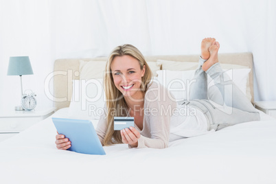 Smiling blonde shopping on line with tablet