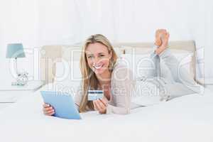 Smiling blonde shopping on line with tablet