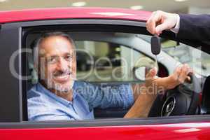 Smiling man driving a car while salesman his giving key