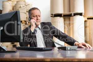Warehouse manager using telephone and laptop