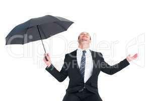 Businessman sheltering under black umbrella testing