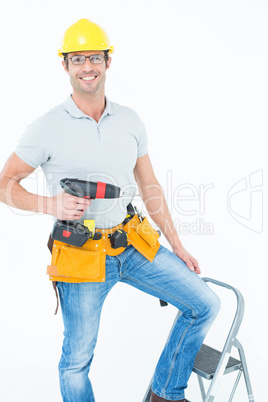 Worker holding drill machine on step ladder