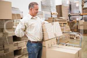 Worker with backache while lifting box in warehouse