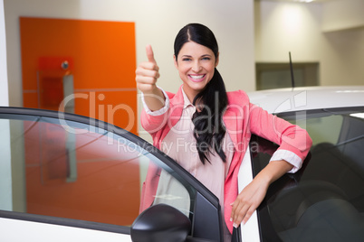 Smiling customer leaning on car while giving thumbs up