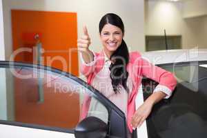 Smiling customer leaning on car while giving thumbs up