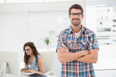 Smiling man with arm crossed standing in front of his colleague