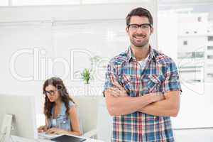 Smiling man with arm crossed standing in front of his colleague