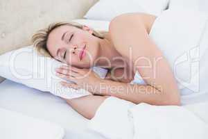 Cheerful blonde woman lying in bed