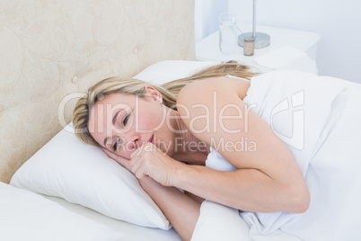 Exhausted blonde woman crying in bed