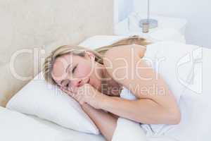 Exhausted blonde woman crying in bed