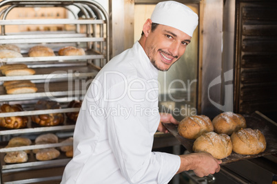 Happy baker taking out fresh loaves