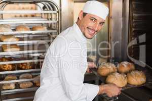 Happy baker taking out fresh loaves