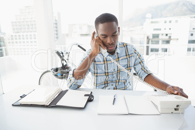 Serious businessman reading desk diary and phoning