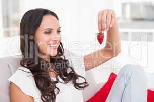 Pretty brunette eating strawberries on couch