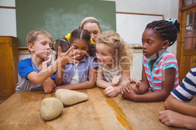 Cute pupils looking through magnifying glass