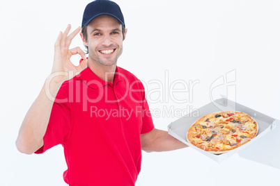 Delivery man gesturing okay while holding fresh pizza