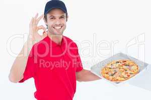 Delivery man gesturing okay while holding fresh pizza