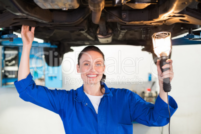 Mechanic shining torch under car