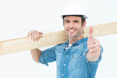 Confident carpenter carrying wooden plank