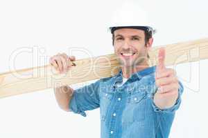 Confident carpenter carrying wooden plank