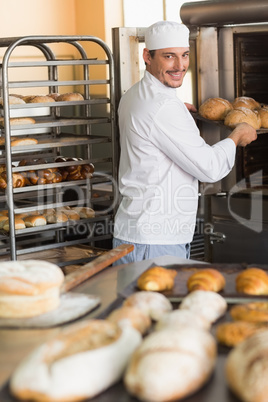 Happy baker taking out fresh loaves