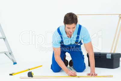 Worker marking on wood while measuring