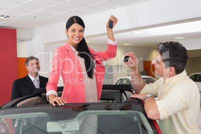 Woman standing in red cabriolet and man taking picture Woman standing in red cabriolet and man taking picture