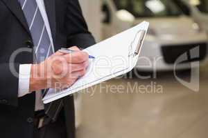 Close up of businessman writing on clipboard