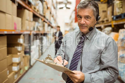 Warehouse manager writing on clipboard