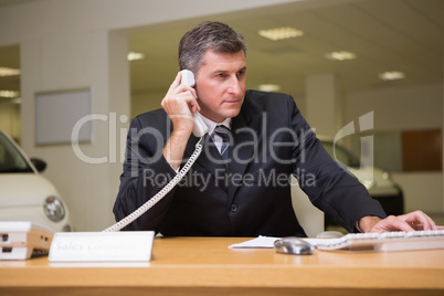 Focused businessman using laptop on the phone