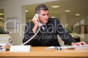 Focused businessman using laptop on the phone