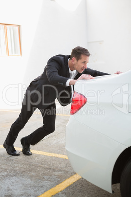 Businessman pushing his broken down car