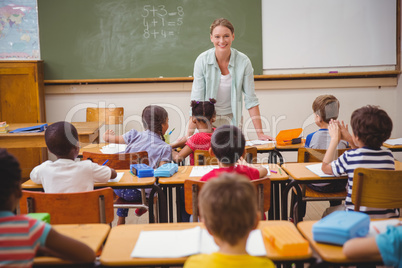 Pretty teacher talking to the young pupils in classroom