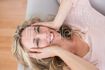 Happy blonde lying on couch with hand on head Happy blonde lying on couch with hand on head