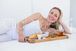 Happy blonde lying and having breakfast in bed