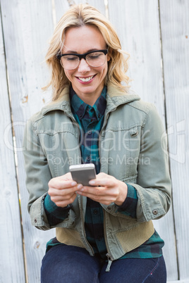 Happy blonde in glasses text messaging