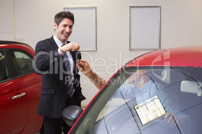 Businessman giving car key while shaking a customer hand