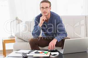 Thoughtful man hand on chin using calculator