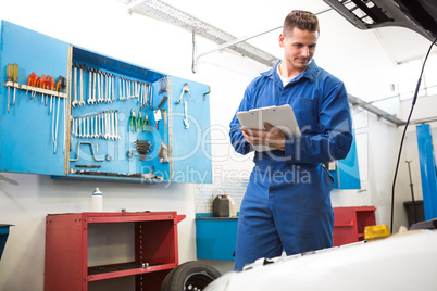 Mechanic examining under hood of car