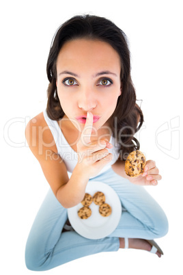 Pretty brunette eating plate of cookies