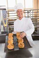 Happy baker holding tray of fresh bread